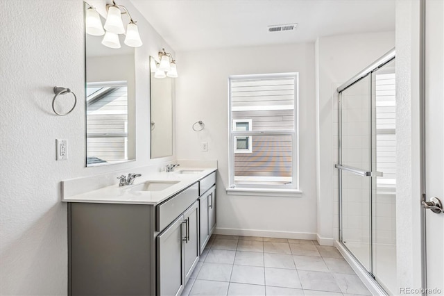 bathroom with a stall shower, visible vents, and a sink