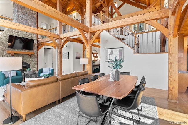 dining space featuring hardwood / wood-style floors, a stone fireplace, and high vaulted ceiling