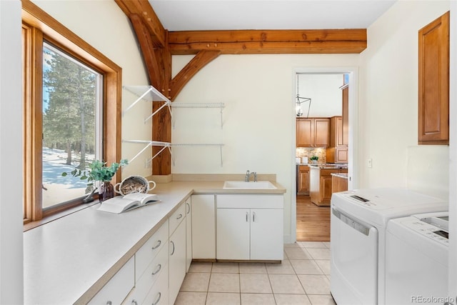 laundry area featuring light tile patterned flooring, cabinets, washer and clothes dryer, and sink