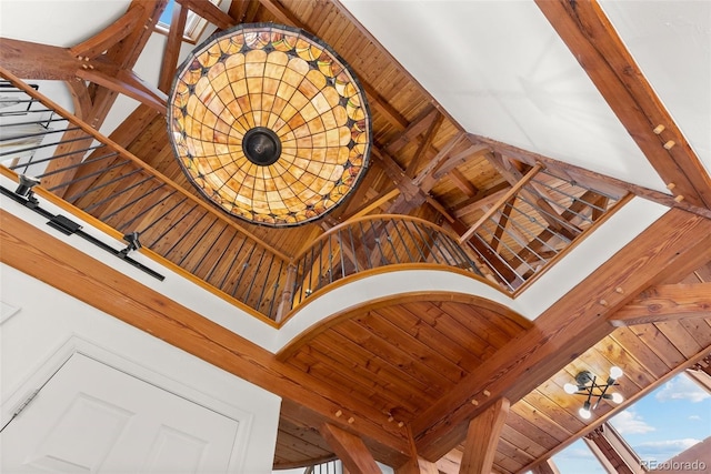 stairs featuring beamed ceiling, wooden ceiling, and high vaulted ceiling