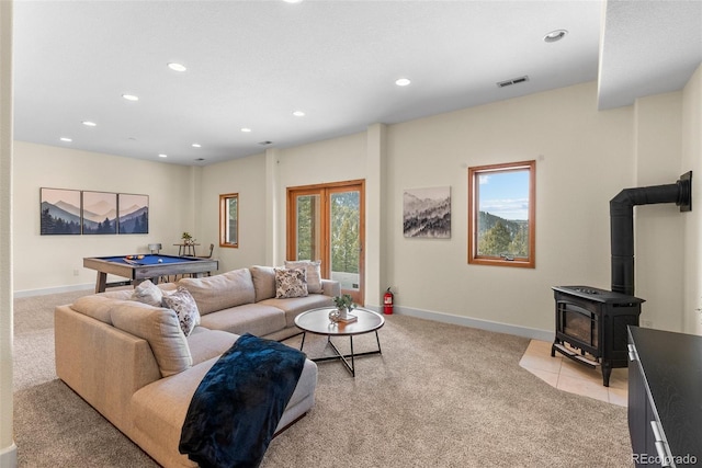 living room featuring plenty of natural light, a wood stove, light colored carpet, and pool table