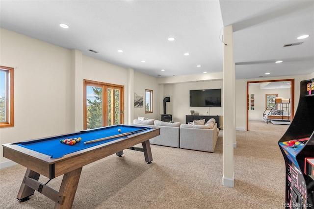 recreation room with a wood stove, light carpet, and billiards