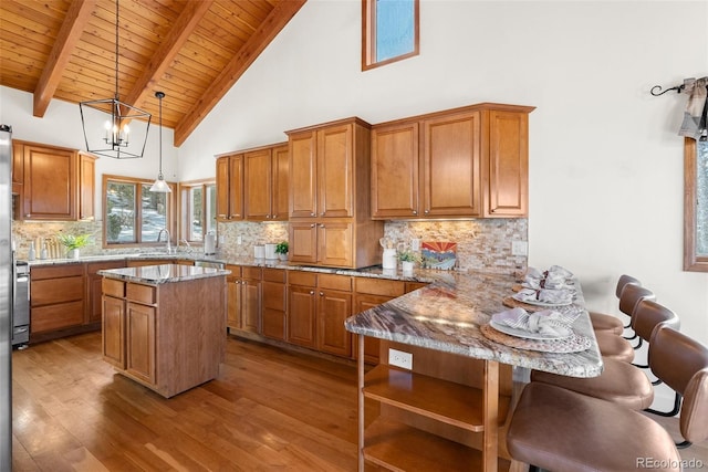 13326 Kuehster Rd, Littleton, CO 80127 - kitchen featuring wooden ceiling, brown cabinetry, light stone counters, a sink, and hardwood / wood-style floors