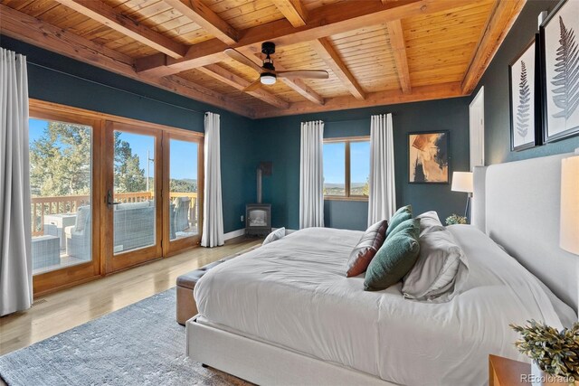 13326 Kuehster Rd, Littleton, CO 80127 - bedroom with wooden ceiling with exposed beams, a wood stove, access to outside, wood finished floors, and ceiling fan