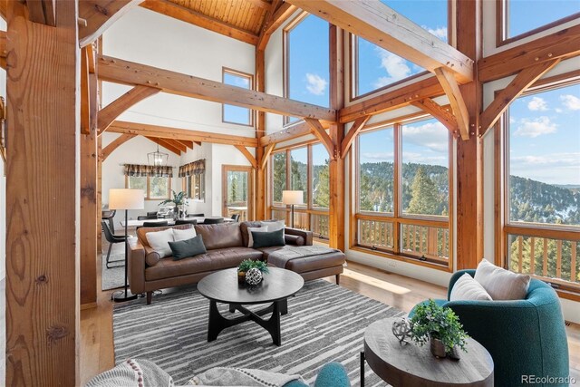 13326 Kuehster Rd, Littleton, CO 80127 - living room featuring wood finished floors, plenty of natural light, high vaulted ceiling, and a chandelier