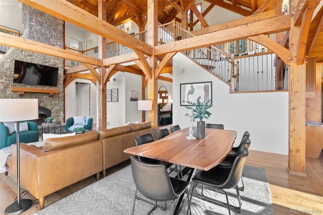 13326 Kuehster Rd, Littleton, CO 80127 - dining room featuring a fireplace, wood finished floors, high vaulted ceiling, beamed ceiling, and stairway