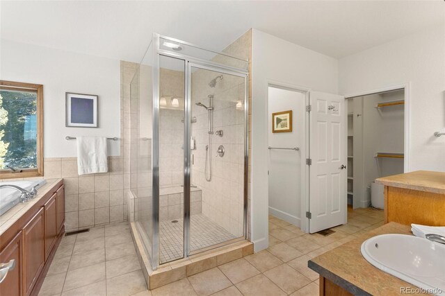 13326 Kuehster Rd, Littleton, CO 80127 - bathroom with a stall shower, vanity, tile patterned flooring, a walk in closet, and tile walls