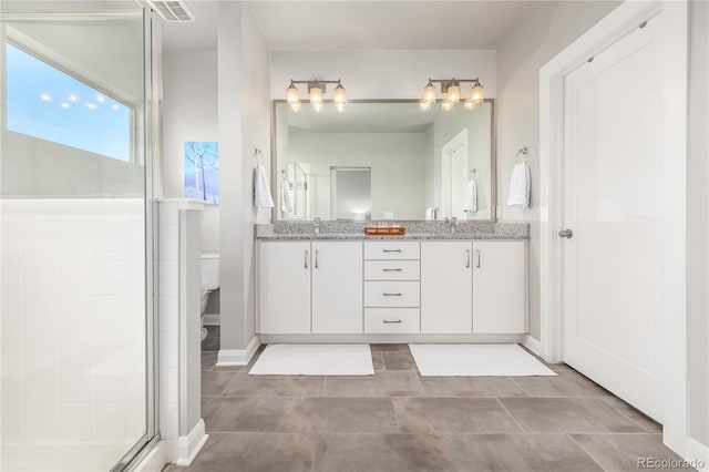 bathroom with vanity, toilet, and a shower with door