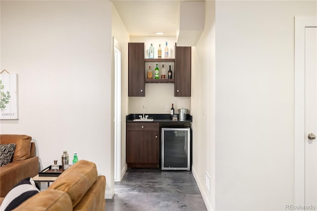 bar featuring dark brown cabinetry, sink, and beverage cooler