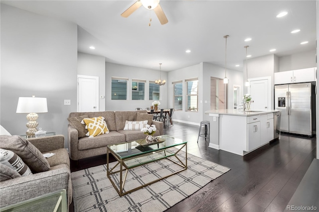 living room featuring ceiling fan with notable chandelier, dark hardwood / wood-style floors, and sink