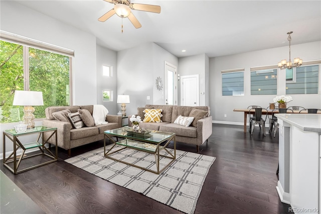 living room featuring ceiling fan with notable chandelier and dark wood-type flooring