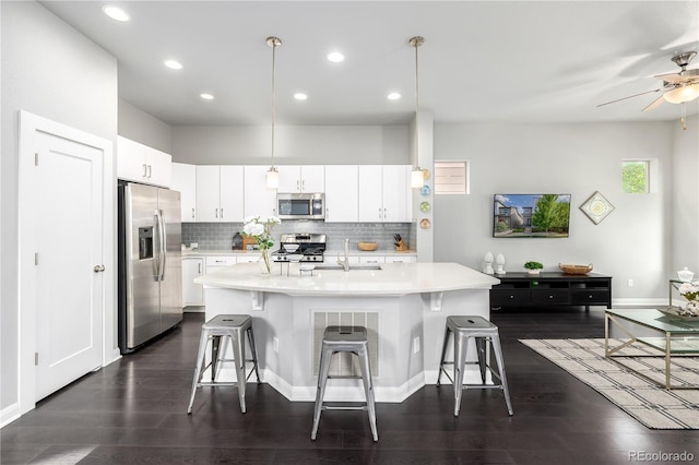 kitchen featuring a breakfast bar, tasteful backsplash, decorative light fixtures, white cabinetry, and stainless steel appliances