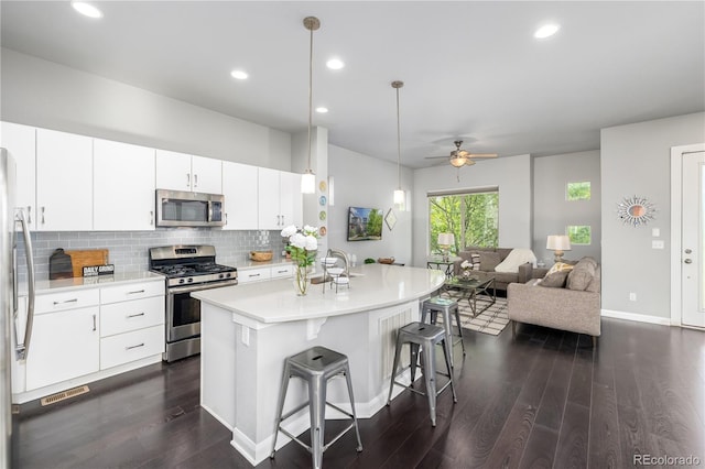 kitchen featuring backsplash, white cabinets, ceiling fan, dark hardwood / wood-style floors, and stainless steel appliances