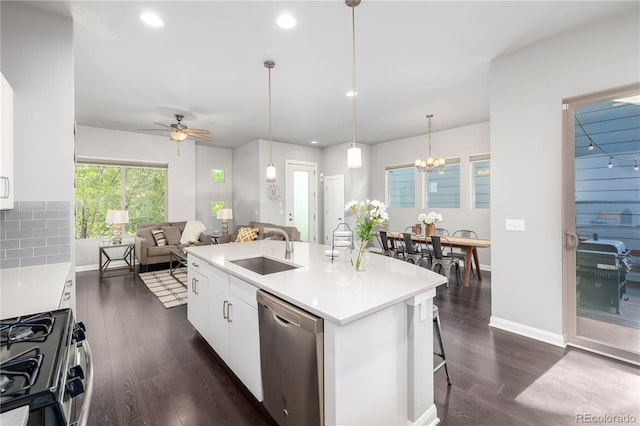 kitchen with appliances with stainless steel finishes, a kitchen island with sink, sink, pendant lighting, and white cabinetry