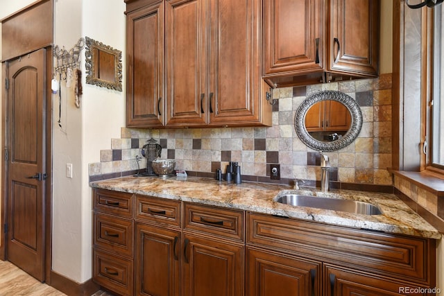 kitchen featuring backsplash, light stone countertops, and sink