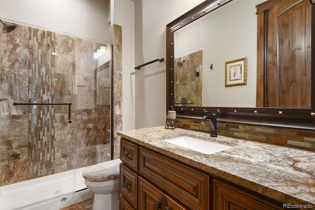 bathroom featuring vanity, a shower with shower door, backsplash, and toilet