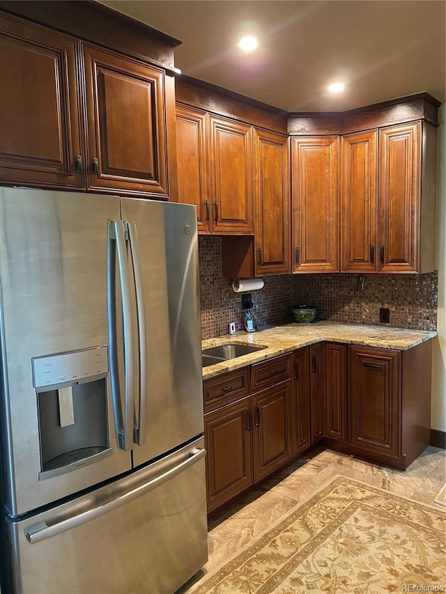 kitchen featuring stainless steel fridge, backsplash, and light stone countertops