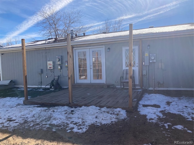 snow covered house with french doors and a deck