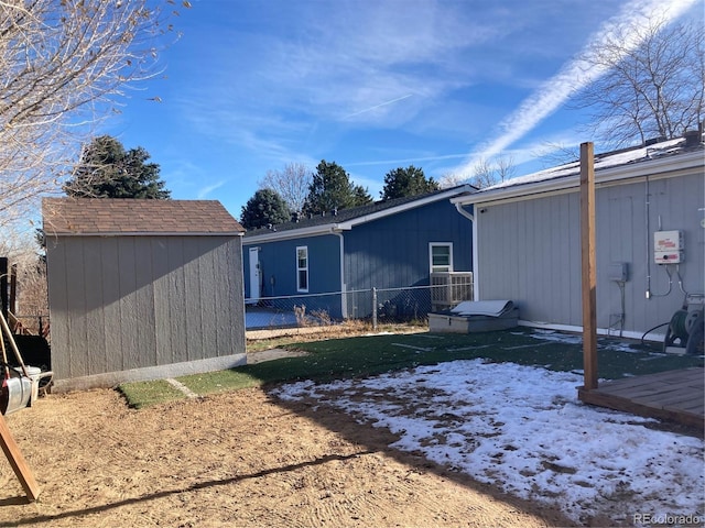 back of house with a storage shed