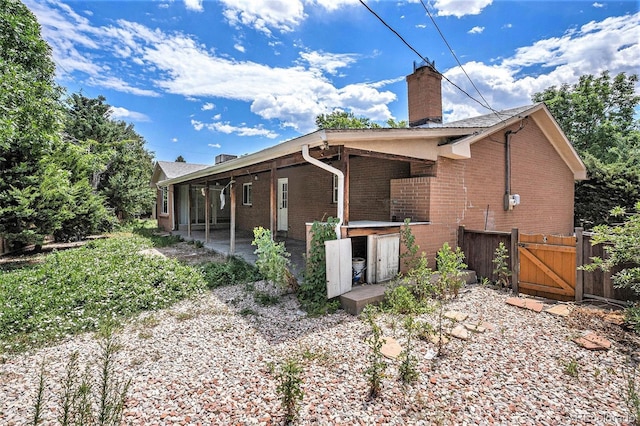 3306 S Uinta Ct, Denver, CO 80231 - back of property with brick siding, a gate, a patio, and a chimney