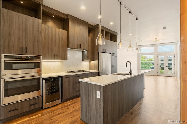 2680 Blake St Unit 4, Denver, CO 80205 - kitchen with appliances with stainless steel finishes, beverage cooler, dark wood finished floors, a center island with sink, and light countertops