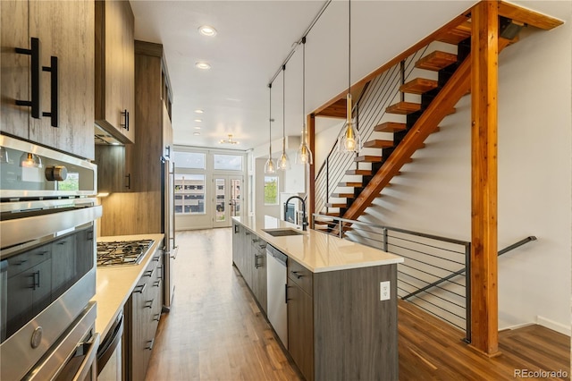 2680 Blake St Unit 4, Denver, CO 80205 - kitchen with stainless steel appliances, a center island with sink, wood finished floors, light countertops, and recessed lighting