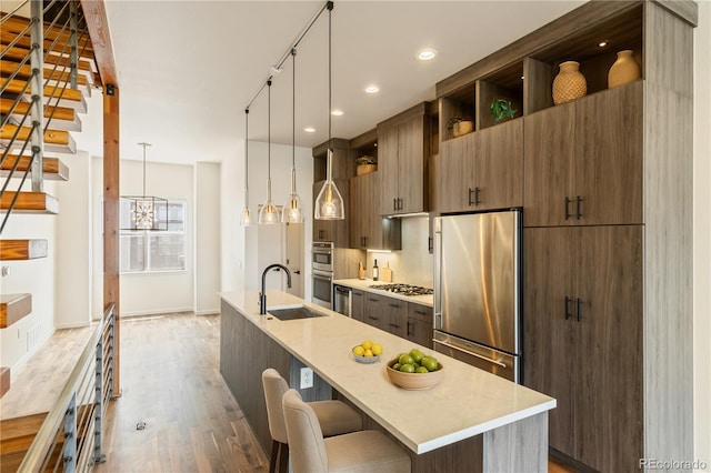2680 Blake St Unit 4, Denver, CO 80205 - kitchen with stainless steel appliances, open shelves, a kitchen island with sink, wood finished floors, and modern cabinets