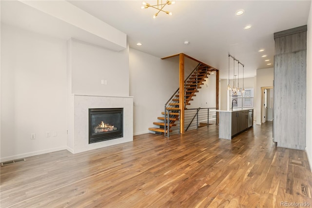 2680 Blake St Unit 4, Denver, CO 80205 - unfurnished living room featuring a chandelier, wood finished floors, a glass covered fireplace, recessed lighting, and stairs