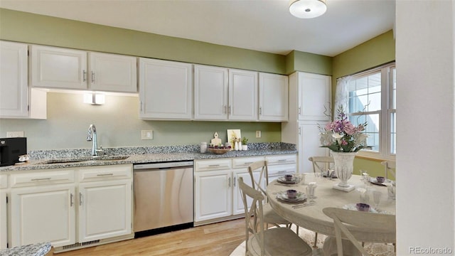 kitchen featuring light hardwood / wood-style floors, sink, light stone counters, dishwasher, and white cabinetry