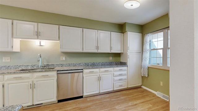 kitchen featuring light wood-type flooring, light stone counters, sink, dishwasher, and white cabinetry