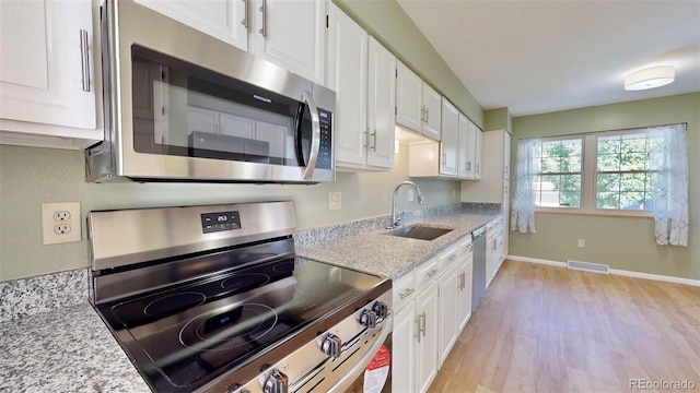 kitchen featuring light hardwood / wood-style floors, sink, stainless steel appliances, light stone countertops, and white cabinets