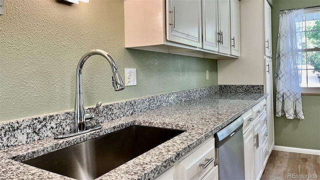 kitchen featuring a wealth of natural light, white cabinets, sink, and stainless steel dishwasher