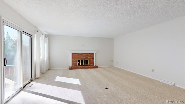 unfurnished living room featuring a brick fireplace, light colored carpet, and a textured ceiling