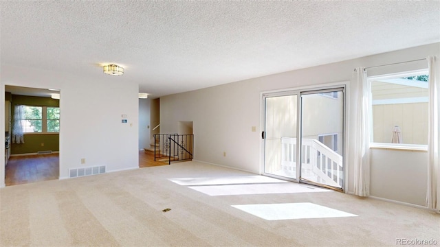 carpeted empty room with a textured ceiling