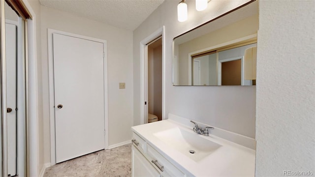 bathroom featuring vanity, toilet, and a textured ceiling