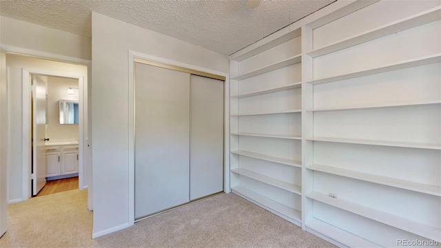 unfurnished bedroom with a closet, light colored carpet, and a textured ceiling