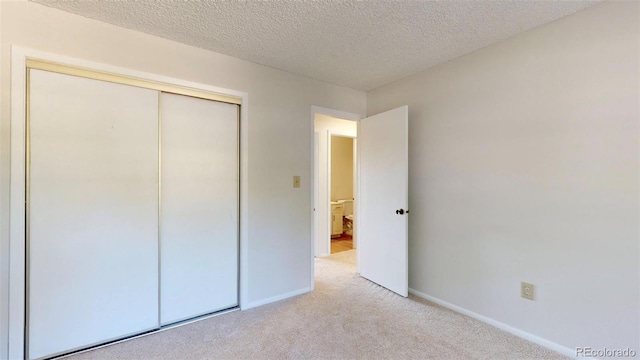 unfurnished bedroom featuring light carpet, a closet, and a textured ceiling