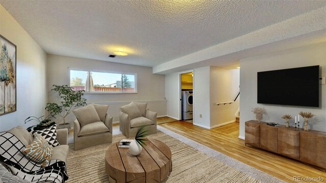 living room featuring hardwood / wood-style flooring, a textured ceiling, and washer / dryer