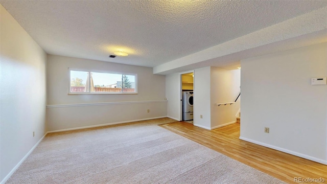 spare room with a textured ceiling, washer / dryer, and light hardwood / wood-style flooring