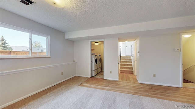 empty room featuring separate washer and dryer, light hardwood / wood-style floors, and a textured ceiling