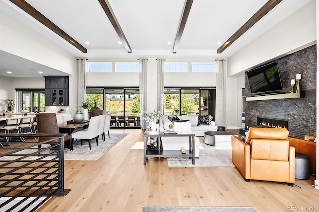 6589 Canyonpoint Rd, Castle Pines, CO 80108 - living area with beamed ceiling, a glass covered fireplace, wood finished floors, and a towering ceiling