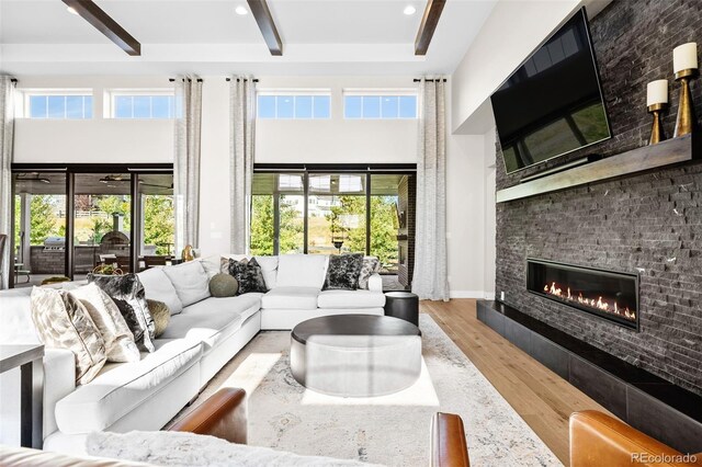 6589 Canyonpoint Rd, Castle Pines, CO 80108 - living area with wood finished floors, a large fireplace, a towering ceiling, beam ceiling, and recessed lighting