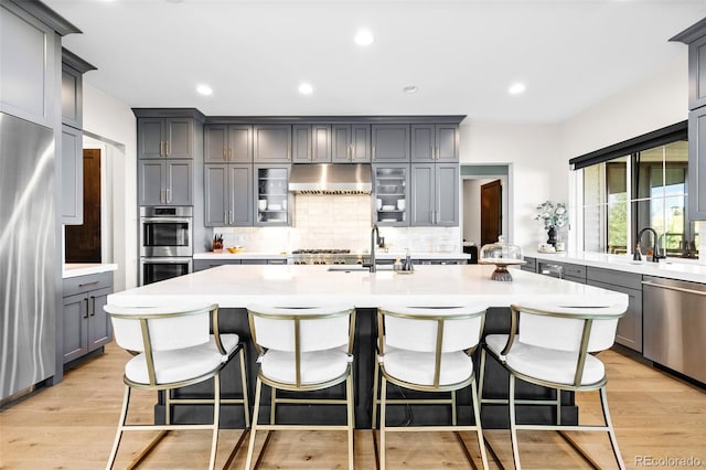 6589 Canyonpoint Rd, Castle Pines, CO 80108 - kitchen with under cabinet range hood, stainless steel appliances, light countertops, backsplash, and gray cabinets