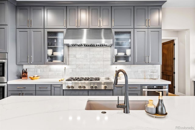 6589 Canyonpoint Rd, Castle Pines, CO 80108 - kitchen featuring gray cabinets, backsplash, under cabinet range hood, and stainless steel appliances