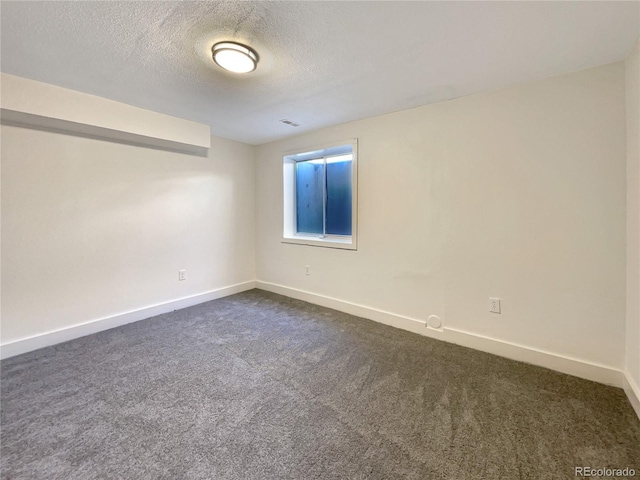 unfurnished room with a textured ceiling and dark carpet