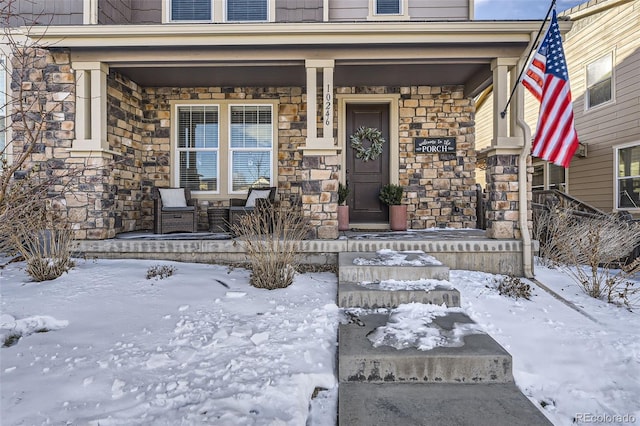 snow covered property entrance with covered porch