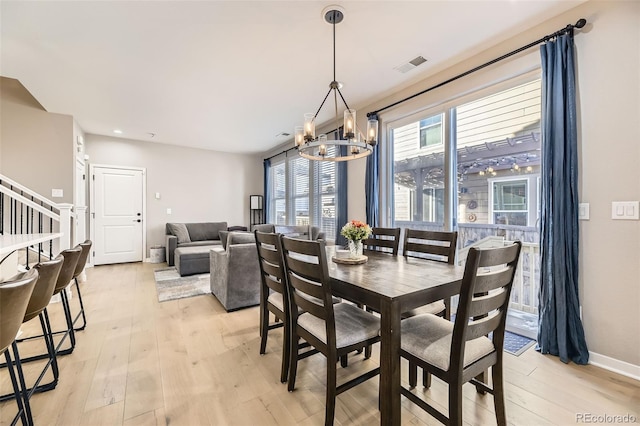 dining room featuring light wood-type flooring, stairs, visible vents, and a chandelier