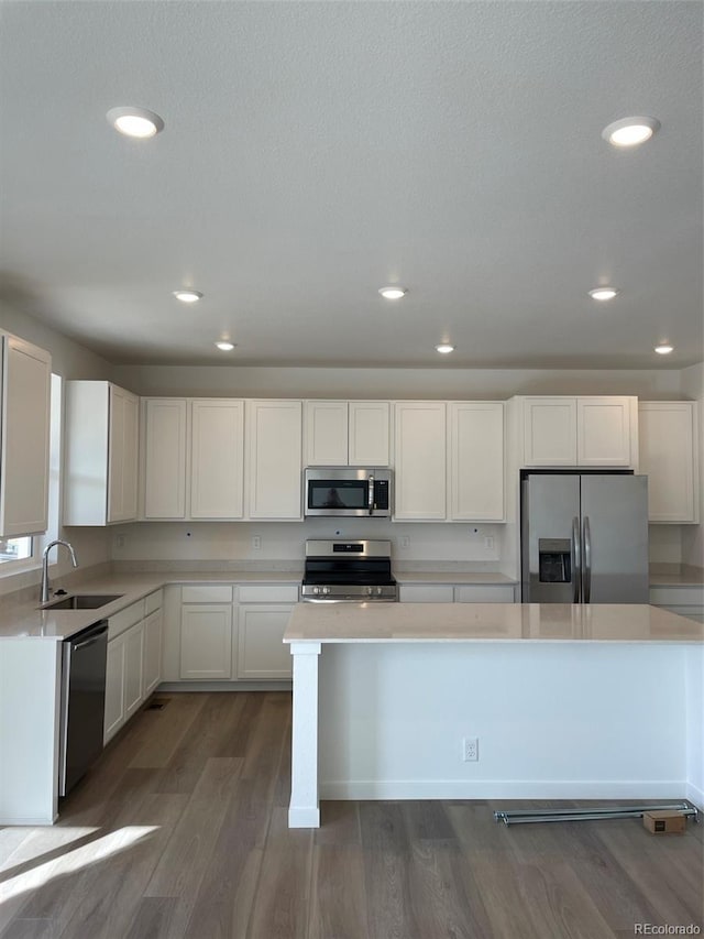 kitchen featuring dark wood-style floors, a sink, stainless steel appliances, light countertops, and white cabinetry