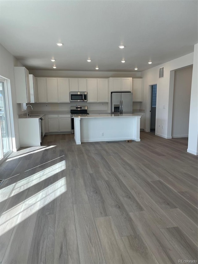 kitchen featuring white cabinetry, wood finished floors, appliances with stainless steel finishes, and a kitchen island