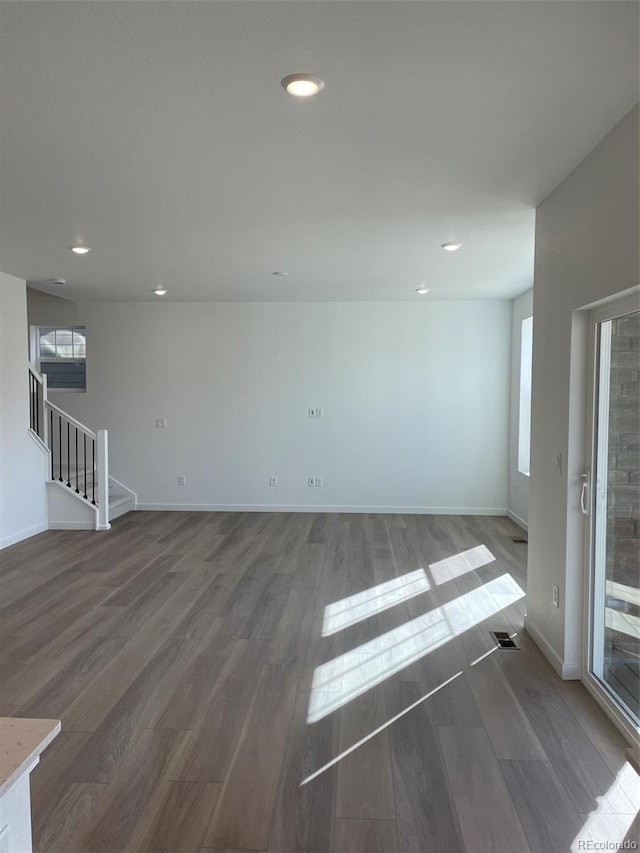 empty room featuring stairway, wood finished floors, and baseboards